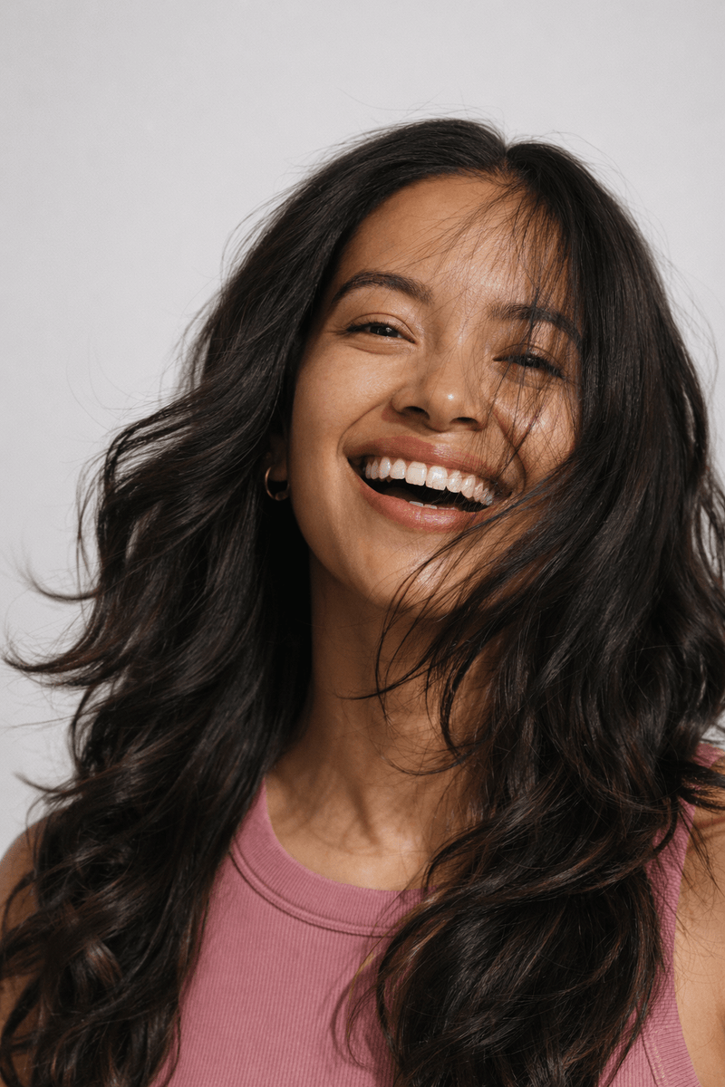 Smiling woman with healthy glowing skin and long wavy dark hair