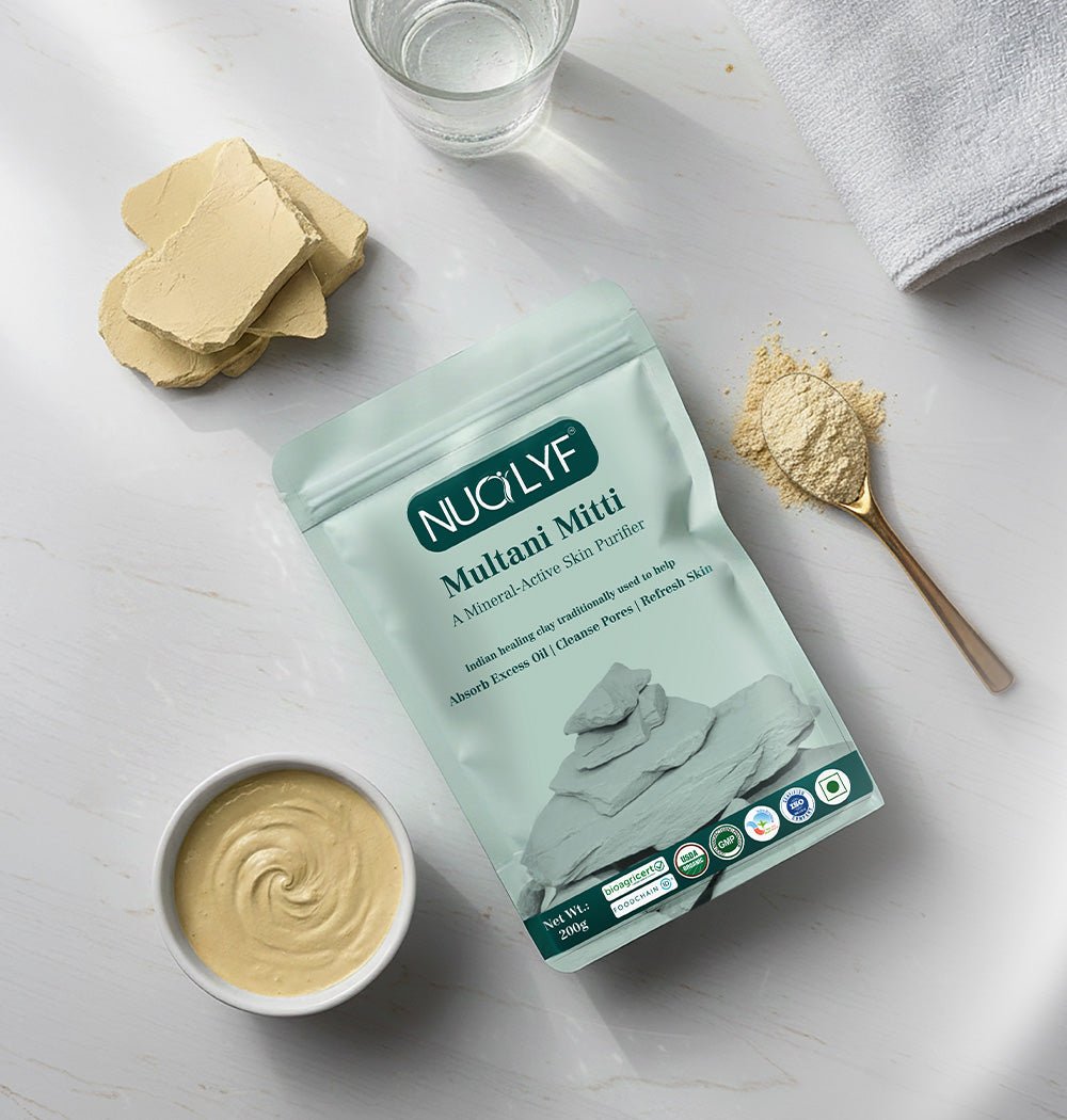Multani Mitti powder pouch with clay pieces, a bowl of face mask, a glass of water, and towel on table