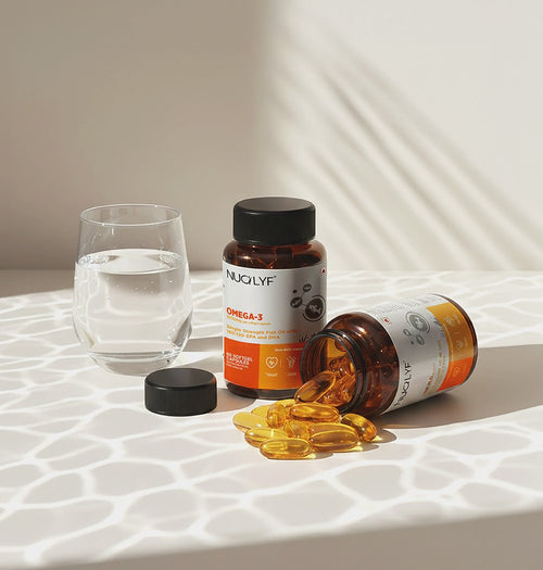 Omega-3 fish oil supplement bottles with softgel capsules and a glass of water on a table.