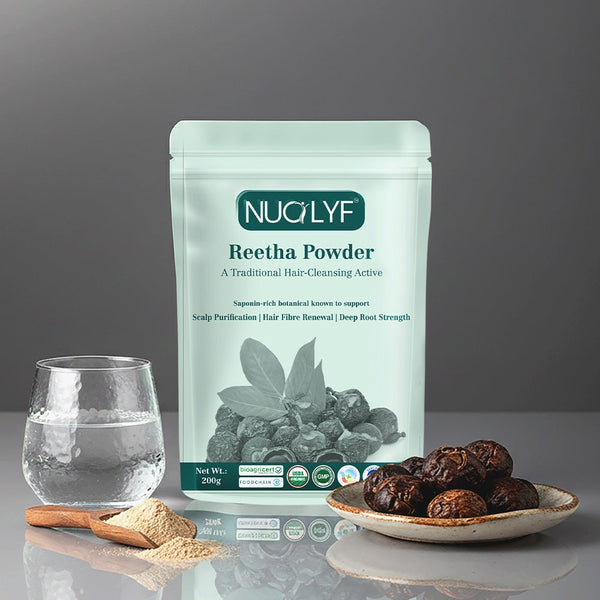 Reetha powder pouch with reetha fruit on a plate, powder in a spoon, and glass of water